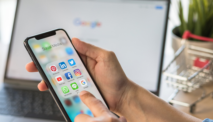 hands holding a smartphone with social media apps on it showcasing what a social media background check can tell you