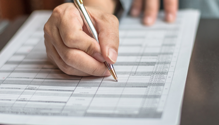 hand holding pen filling on application conducting an education verification check