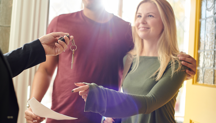 happy couple being given house keys showcasing if a landlord can ask for a background check