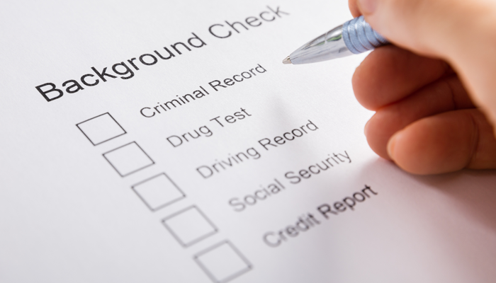 closeup of a background check application and hand holding pen to paper application