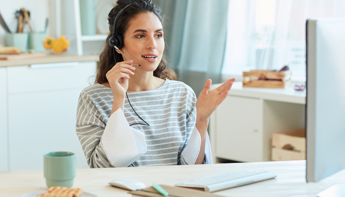 woman at desk with headphones looking at computer working