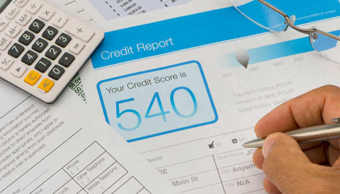 image of a credit report with the credit score of 540 and a calculator and application scattered on table