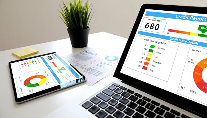 image of a tablet and laptop on a desk with a credit report showing the credit score of 680 indicating the requirement of a credit check