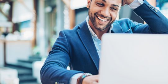 Young Middle Eastern ethnicity businessman looking at his laptop with happiness and excitement.