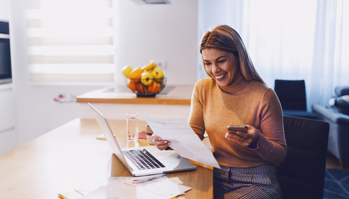 smiling woman sitting in kitchen table overlooking piece of paper showcasing reference check verifications