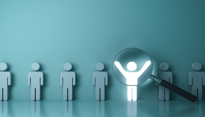 blue standing body shapes with one highlighted white with hands up focussed on with a magnifying glass