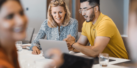 male and female HR professionals rescreening their employees looking at laptop smiling.