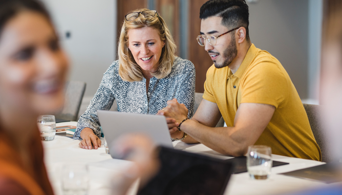 male and female HR professionals rescreening their employees looking at laptop smiling.