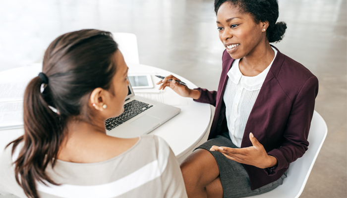 2 women professionals sitting at a desk conducting interviews using employment background check