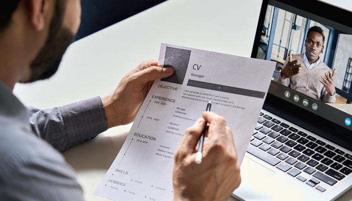 man on laptop job hunting in canada being interviewed and interviewer holding his CV