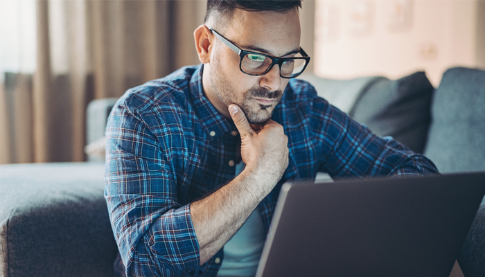 man intently looking at laptop screen for jobs at indeed canada
