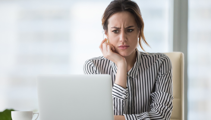 woman looking at laptop with confused look on her face indicating looking at a scam job posting