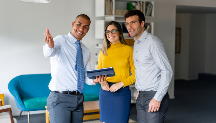 real estate recruitment office with 3 professionals standing in an office looking ahead with smiles