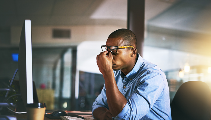 young african american man with hands pinching between his eyes looking stressed for the cause of stress in the workplace