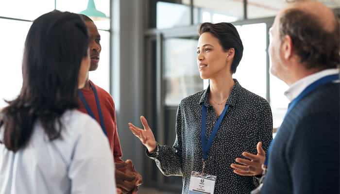 4 professionals standing in a group having a conversation showcasing networking in canada