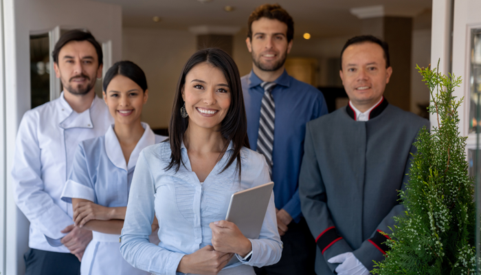 5 hotel management professionals standing and smiling indicating filling hotel management roles with confidence