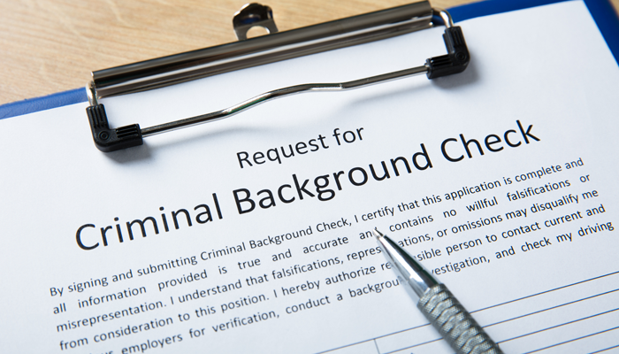 clipboard with a request for a criminal background check on it and a pen