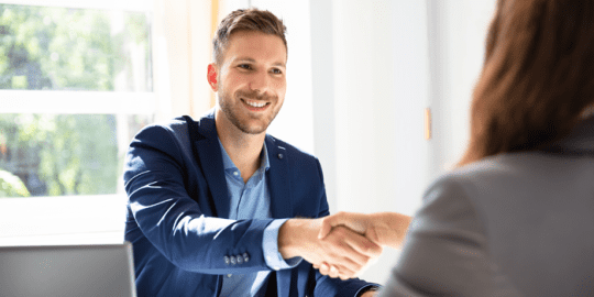 sharply dressed young man shaking hands of a woman reflecting that he was given employment after a canadian background check