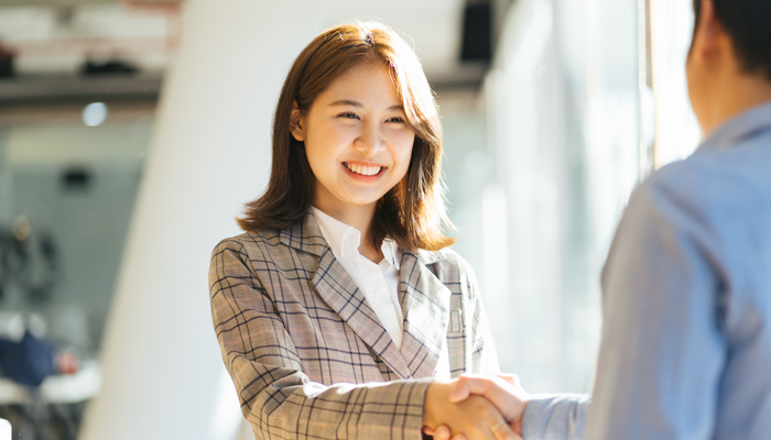 young asian woman shaking the hand of a professional after completing an online police check