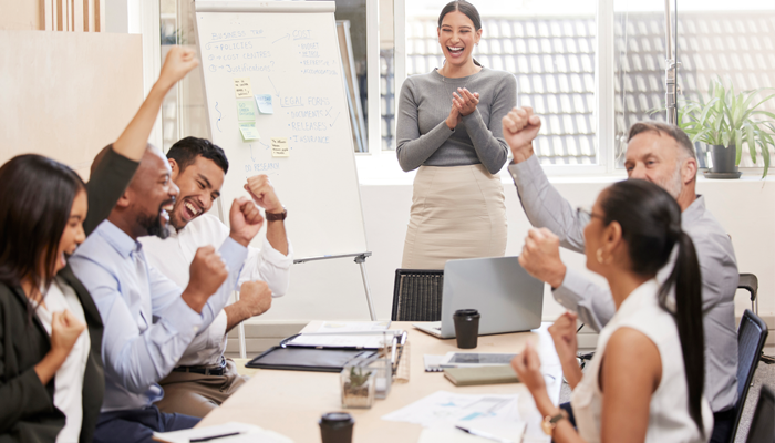 group of employees sitting around desk cheering after completing their social media checks