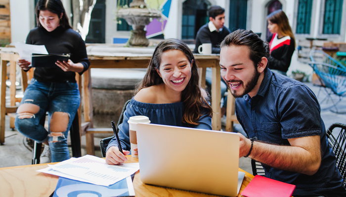 young man and woman sitting at desk looking at computer for summer jobs for uni students