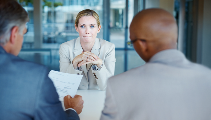 professional women sitting in front of 2 professional men looking over her education verifications