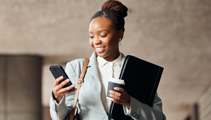 young professional black woman smiling at smartphone getting help with her linkedin profile