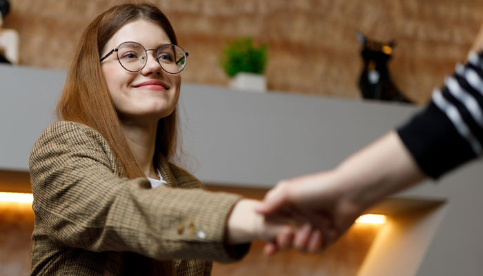 young woman shaking hand of employer after a criminal background check landed her a job