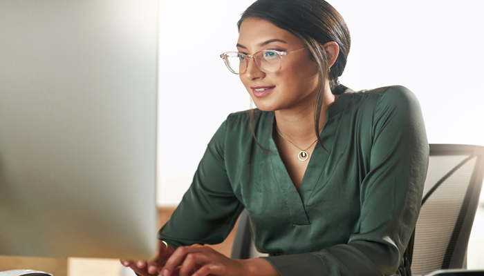 young woman smiling at computer showcasing her looking over results of criminal record check online